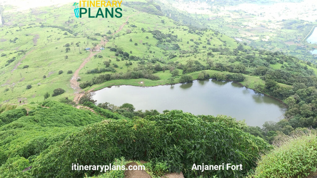 A serene aerial view of a lush green landscape with a small, oval-shaped lake surrounded by trees. The tone is tranquil and natural.