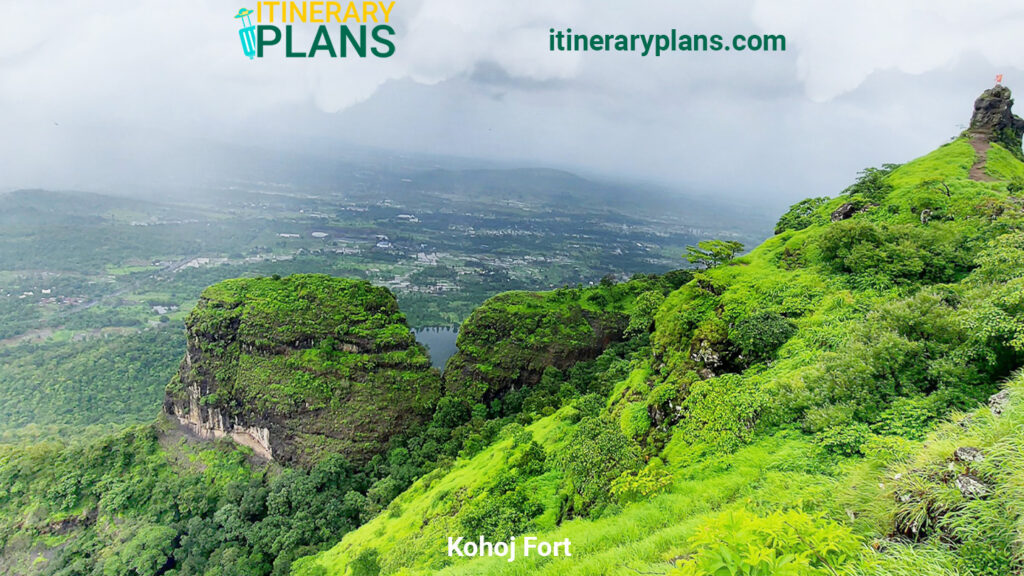 Lush green landscape of Kohoj Fort, Maharashtra, with rocky outcrops shrouded in mist. The scene conveys tranquility and natural beauty.