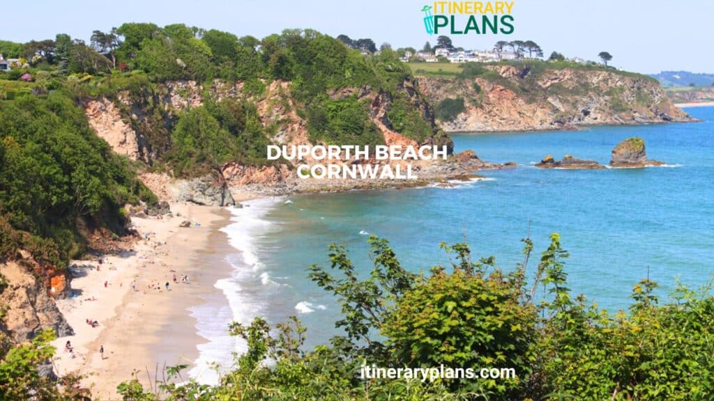 Scenic view of Duporth Beach Cornwall with golden sands, turquoise waters, lush greenery, and cliffs in a tranquil coastal setting.