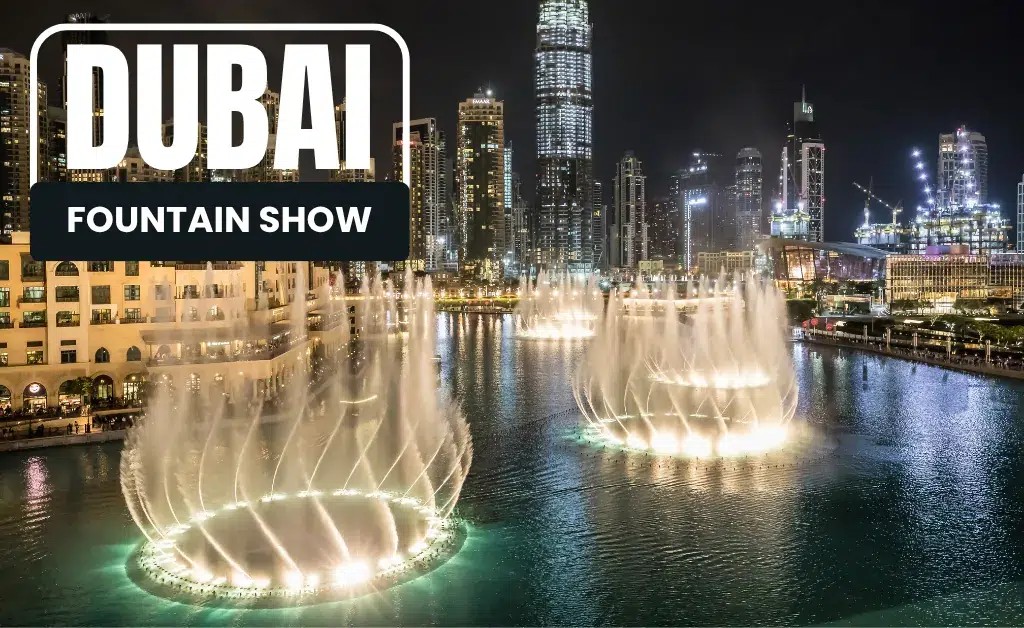 Dubai Fountain Show at night with illuminated water jets in sync. Skyscrapers form the backdrop, creating a vibrant, lively cityscape atmosphere.