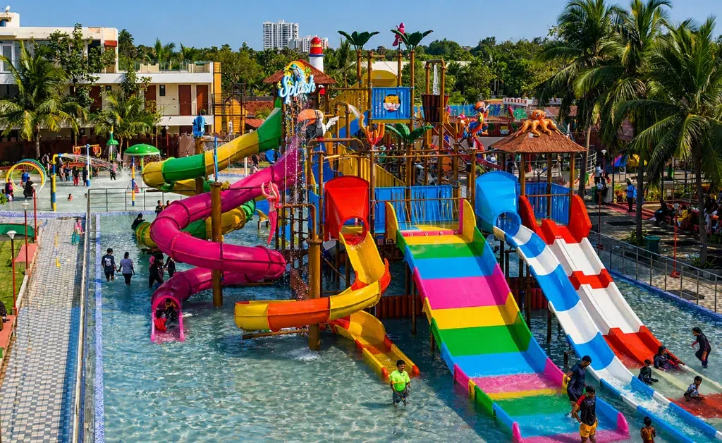 Vibrant water park with colorful slides, splash structures, and palm trees. Families and children enjoy the sunny day, creating a lively, fun atmosphere.