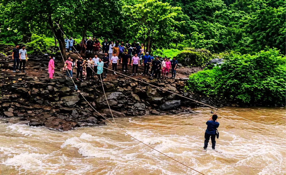 A man uses ropes to cross a turbulent river, observed by a large crowd on a rocky, forested riverbank. The scene conveys tension and curiosity.
