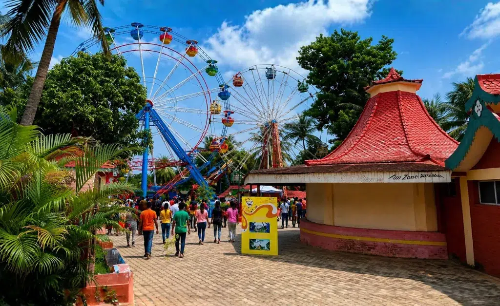 Colorful amusement park scene with vibrant Ferris wheels, lush trees, and a cheerful crowd. Bright sky adds a lively, festive atmosphere.