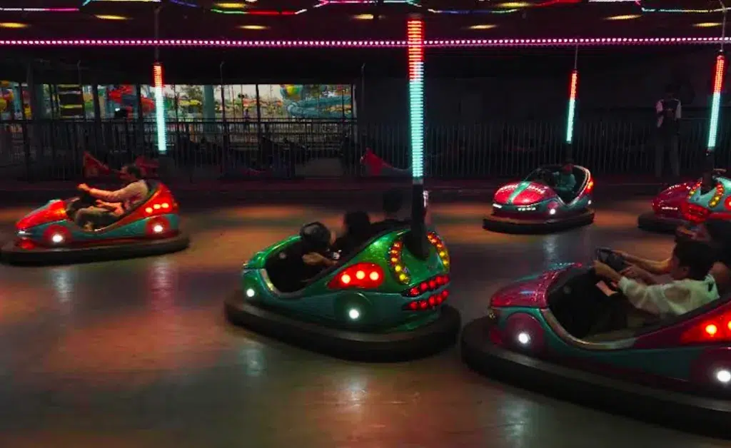 Carnival scene with colorful bumper cars, each glowing with red and green lights. Riders laugh and steer, creating a lively, fun-filled atmosphere.