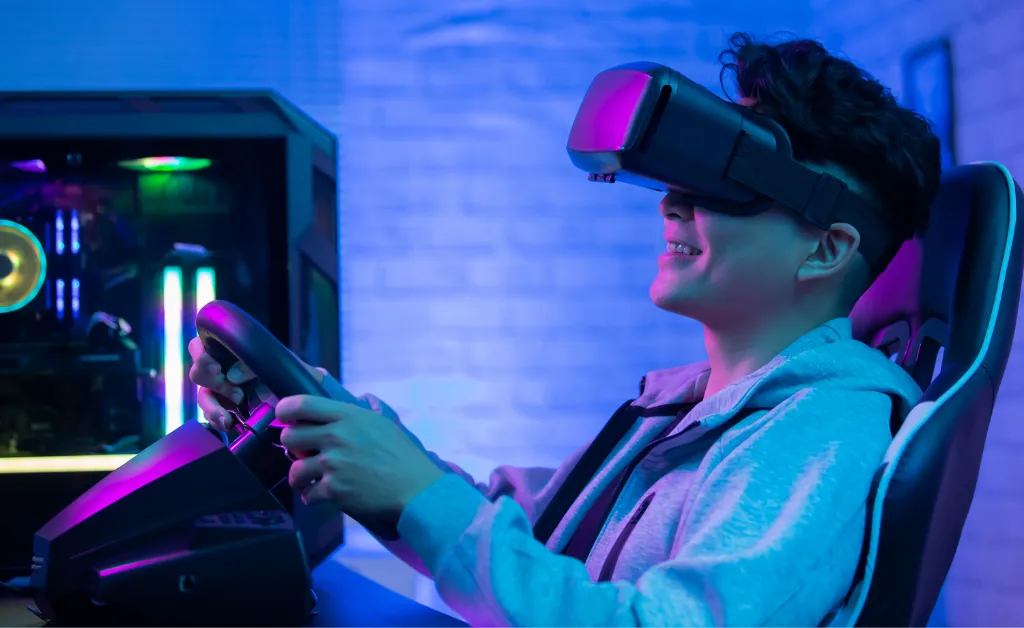 A person wearing a VR headset is smiling while using a racing simulator. The room is lit with blue and purple hues, creating an immersive gaming atmosphere.