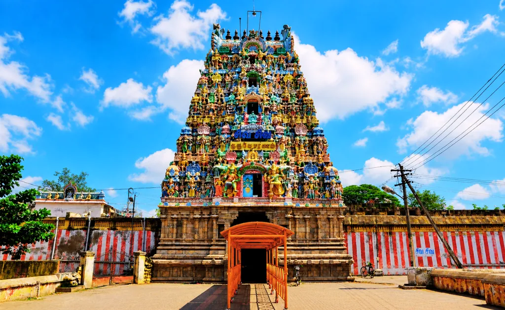 Vibrant South Indian temple with ornate, colorful carvings on a towering gopuram against a bright blue sky, exuding a sense of cultural richness.